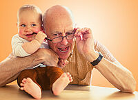 Senior mit einem Baby im Arm, lachen zusammen.