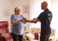 Aktivierungscoach macht Sport mit Seniorin.